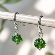 Raw drilled Chlum Moldavite earrings with naturally rounded green stones and rhodium-plated hooks