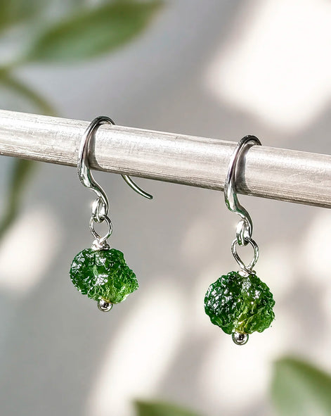 Raw drilled Chlum Moldavite earrings with naturally rounded green stones and rhodium-plated hooks