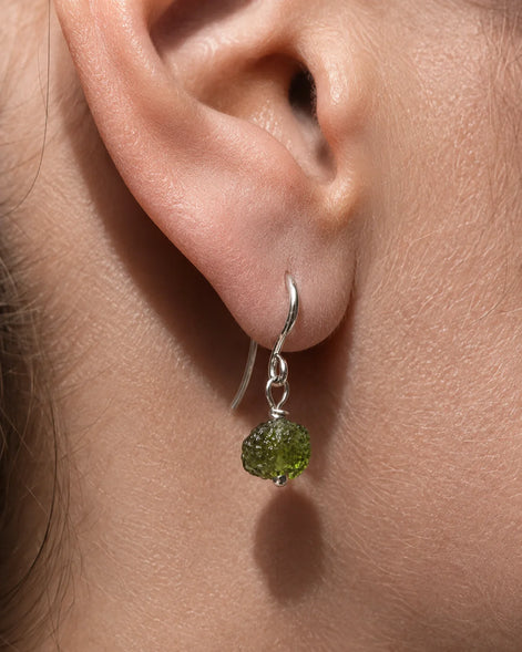 Raw drilled Chlum Moldavite earrings with naturally rounded green stones and rhodium-plated hooks.