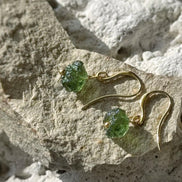 Raw drilled Chlum Moldavite earrings with naturally rounded green stones and gold-plated hooks.
