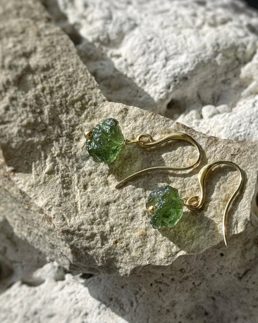 Raw drilled Chlum Moldavite earrings with naturally rounded green stones and gold-plated hooks.