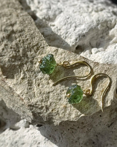 Raw drilled Chlum Moldavite earrings with naturally rounded green stones and gold-plated hooks.