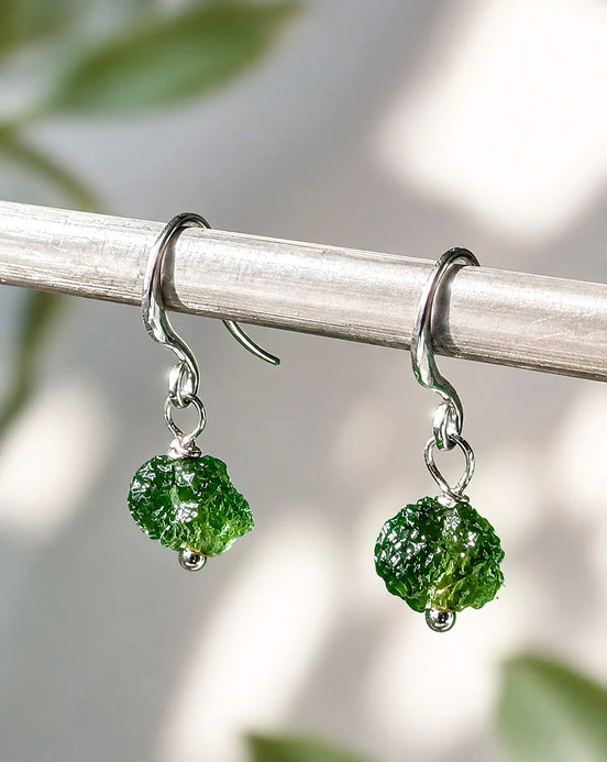 Raw drilled Chlum Moldavite earrings with naturally rounded green stones and rhodium-plated hooks