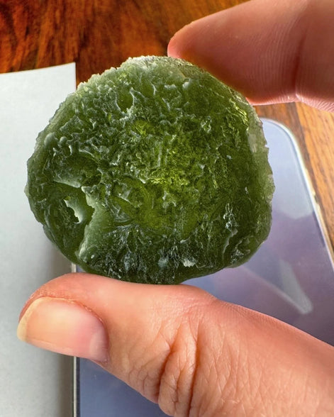 Hand holding 35g Moldavite from Bartochov, Czech Republic