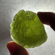 Hand holding a 35g Moldavite from Bartochov, Czech Republic