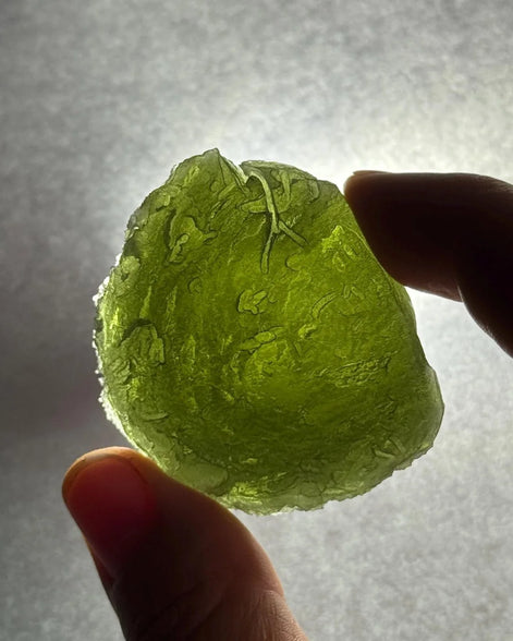 Hand holding a 35g Moldavite from Bartochov, Czech Republic