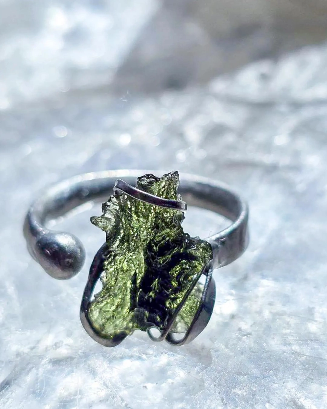 Adjustable moldavite ring with a 0.87g transparent green stone from Nesměň, featuring spiked sculpting in a tin and silver alloy setting.