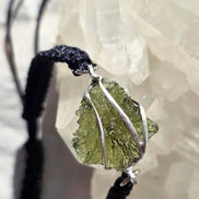 Moldavite bracelet stone held to daylight showing transparency