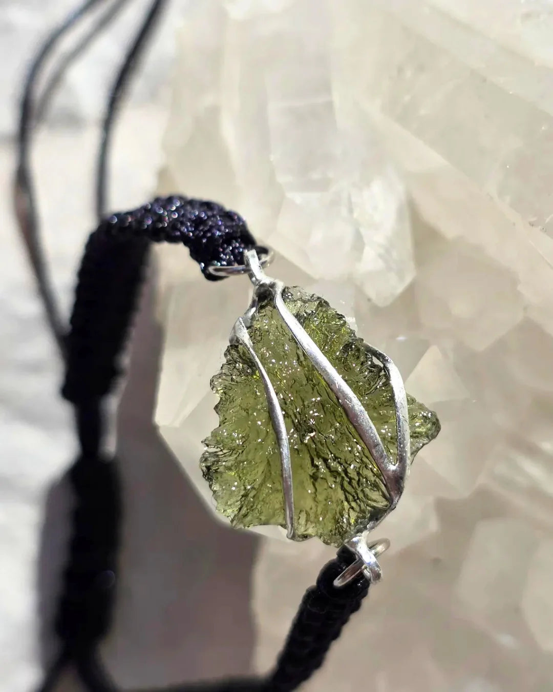 Moldavite bracelet stone held to daylight showing transparency