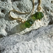 Raw drilled Chlum Moldavite earrings with naturally rounded green stones and gold-plated hooks.