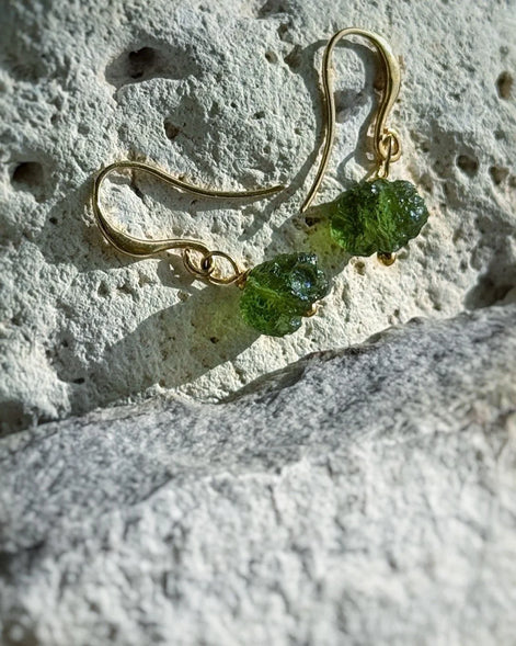 Raw drilled Chlum Moldavite earrings with naturally rounded green stones and gold-plated hooks.