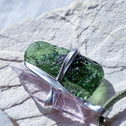 Pendant with 3.49g apple green moldavite from Ločenice and pale pink kunzite held by crossing metal bands.