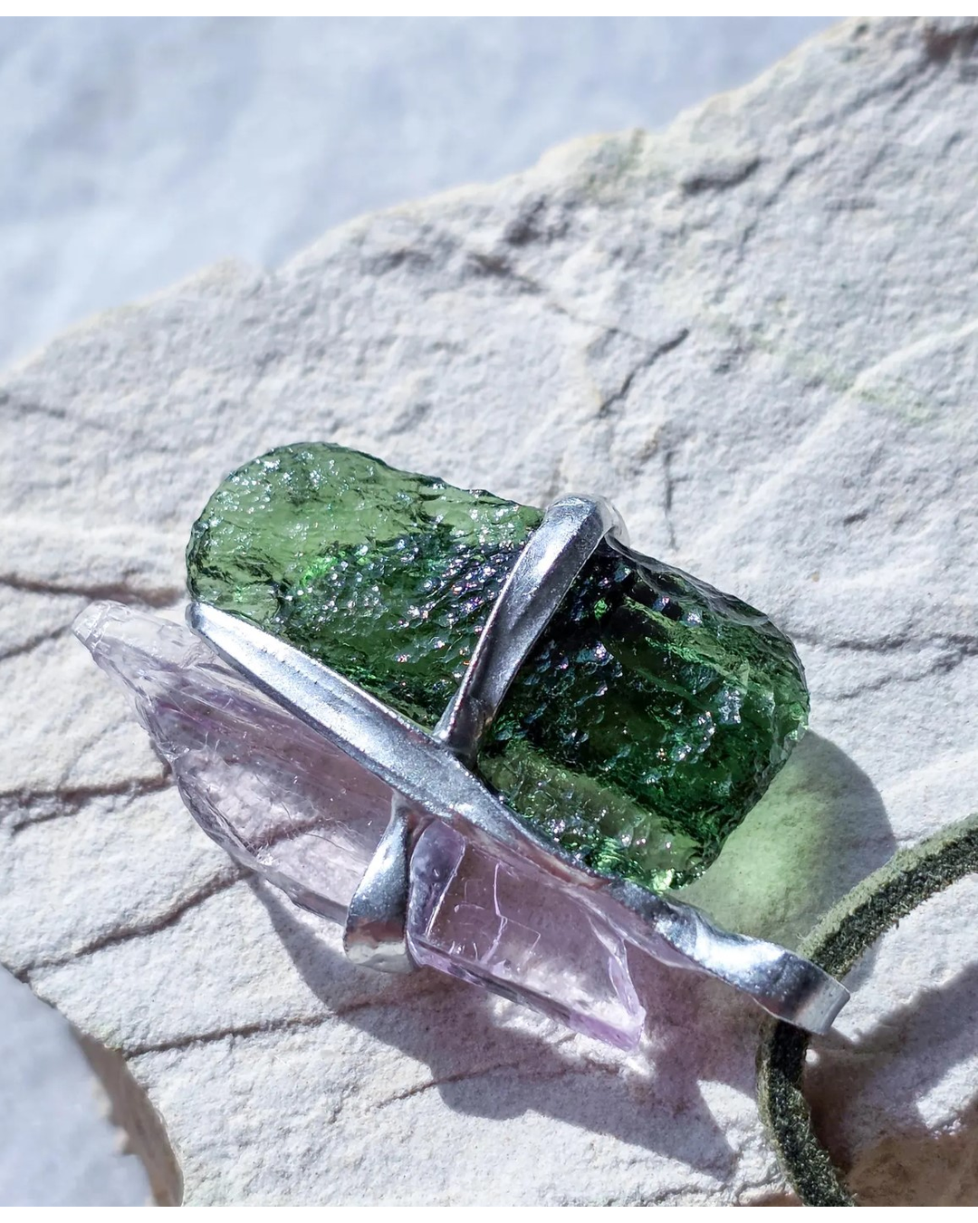 Pendant with 3.49g apple green moldavite from Ločenice and pale pink kunzite held by crossing metal bands.