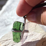 Pendant with 3.49g apple green moldavite from Ločenice and pale pink kunzite held by crossing metal bands.