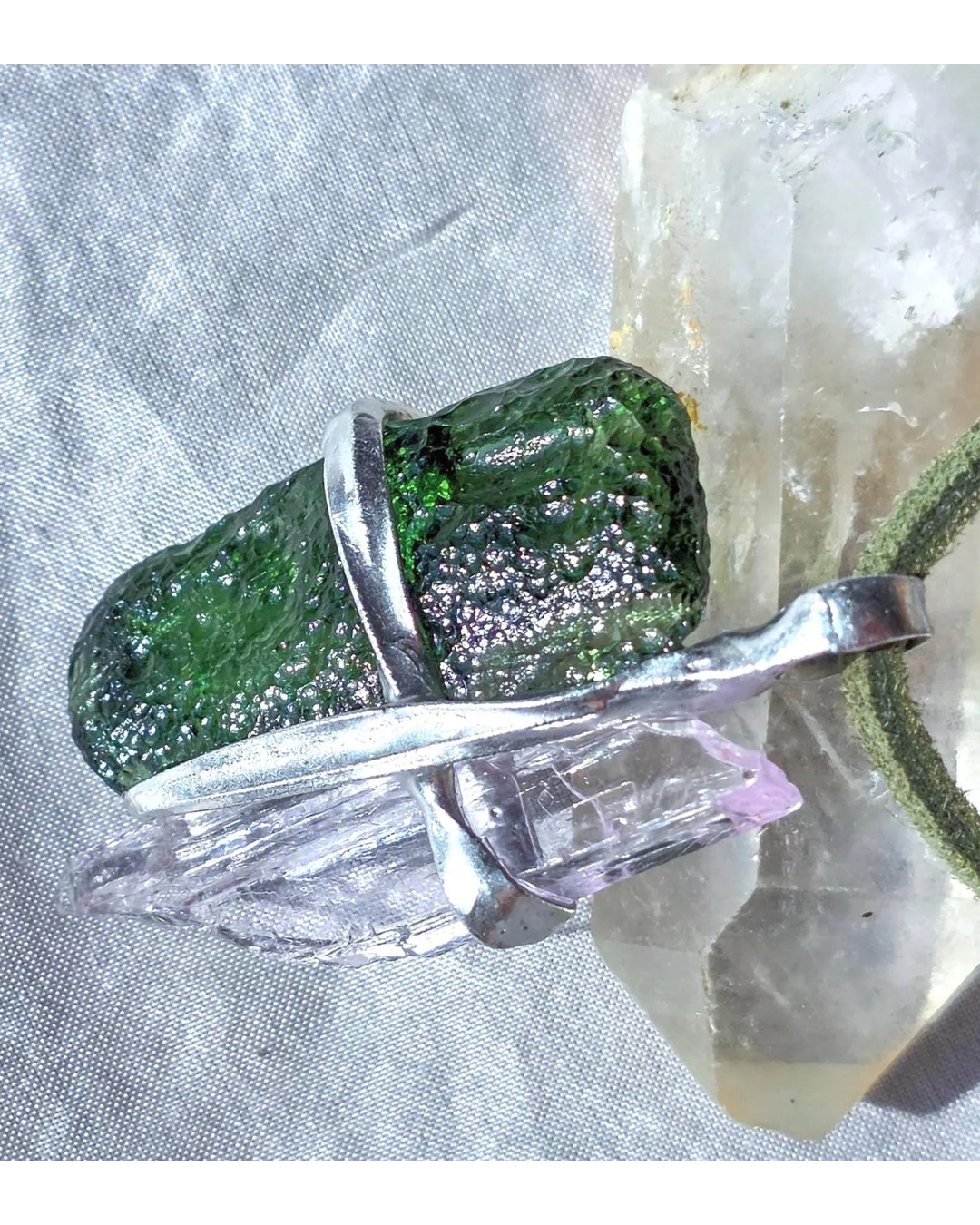 Pendant with 3.49g apple green moldavite from Ločenice and pale pink kunzite held by crossing metal bands.