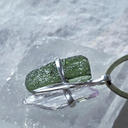 Pendant with 3.49g apple green moldavite from Ločenice and pale pink kunzite held by crossing metal bands.