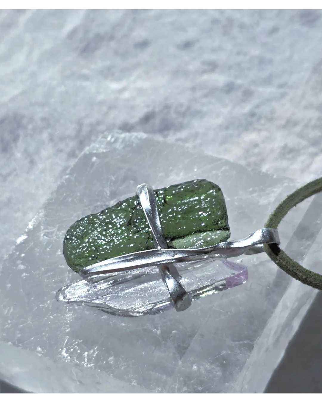 Pendant with 3.49g apple green moldavite from Ločenice and pale pink kunzite held by crossing metal bands.