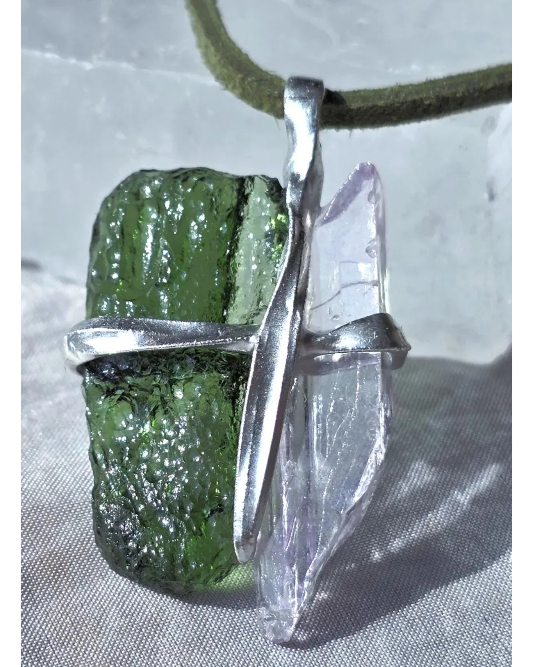 Pendant with 3.49g apple green moldavite from Ločenice and pale pink kunzite held by crossing metal bands.