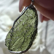 Close-up of a raw Chlum Moldavite pendant in an open handcrafted setting