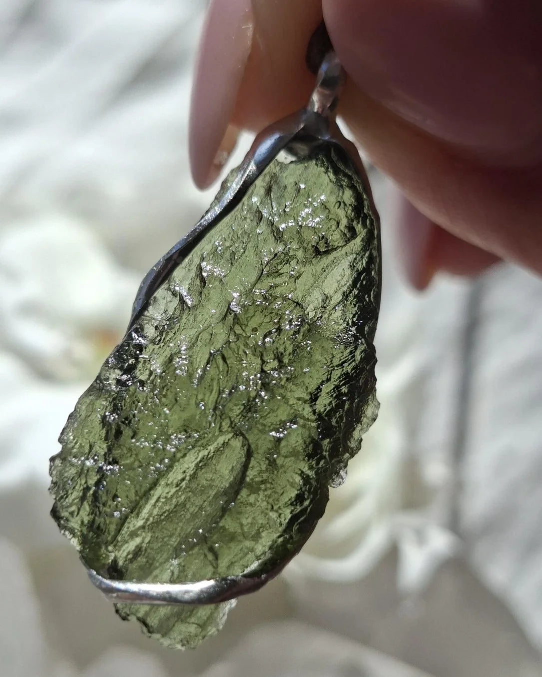 Close-up of a raw Chlum Moldavite pendant in an open handcrafted setting