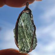 Hand holding a raw Moldavite pendant with a transparent 3.14 g Chlum stone back-side